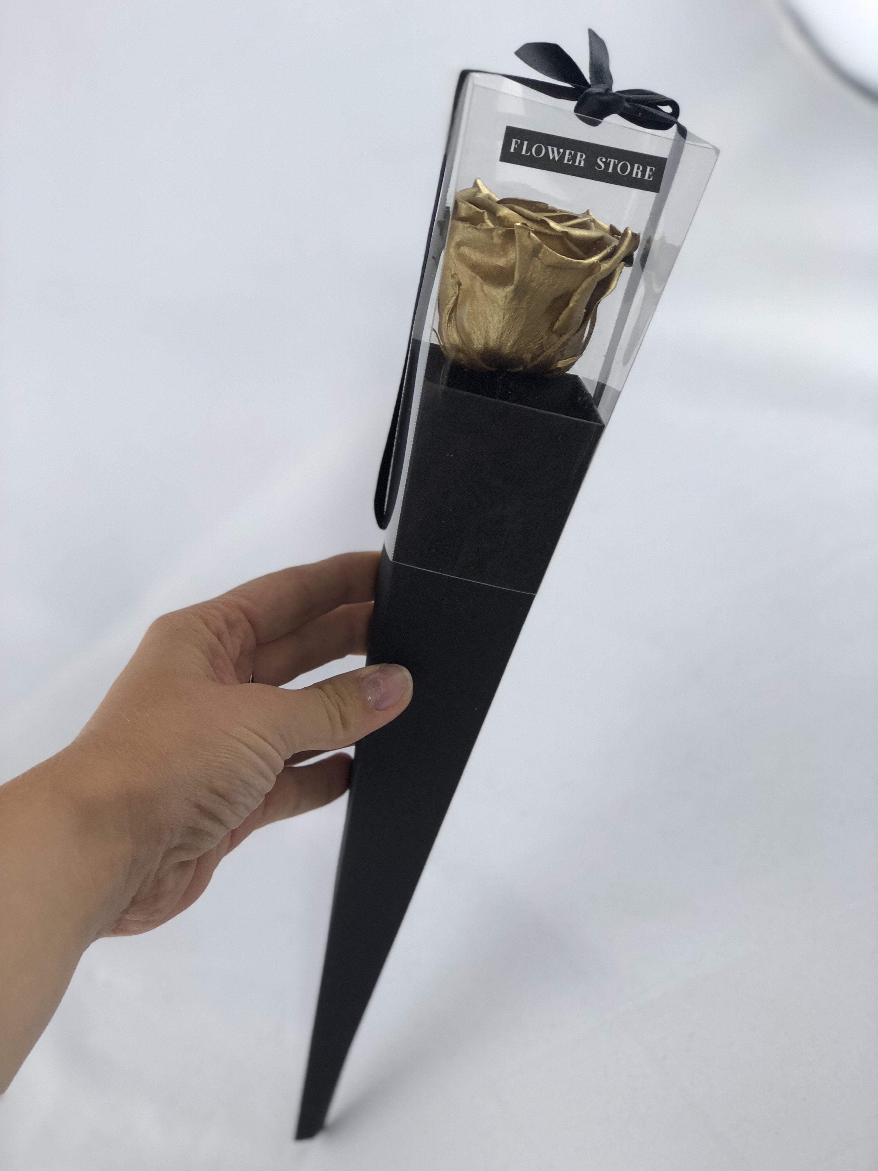 A golden eternal rose in a black cone