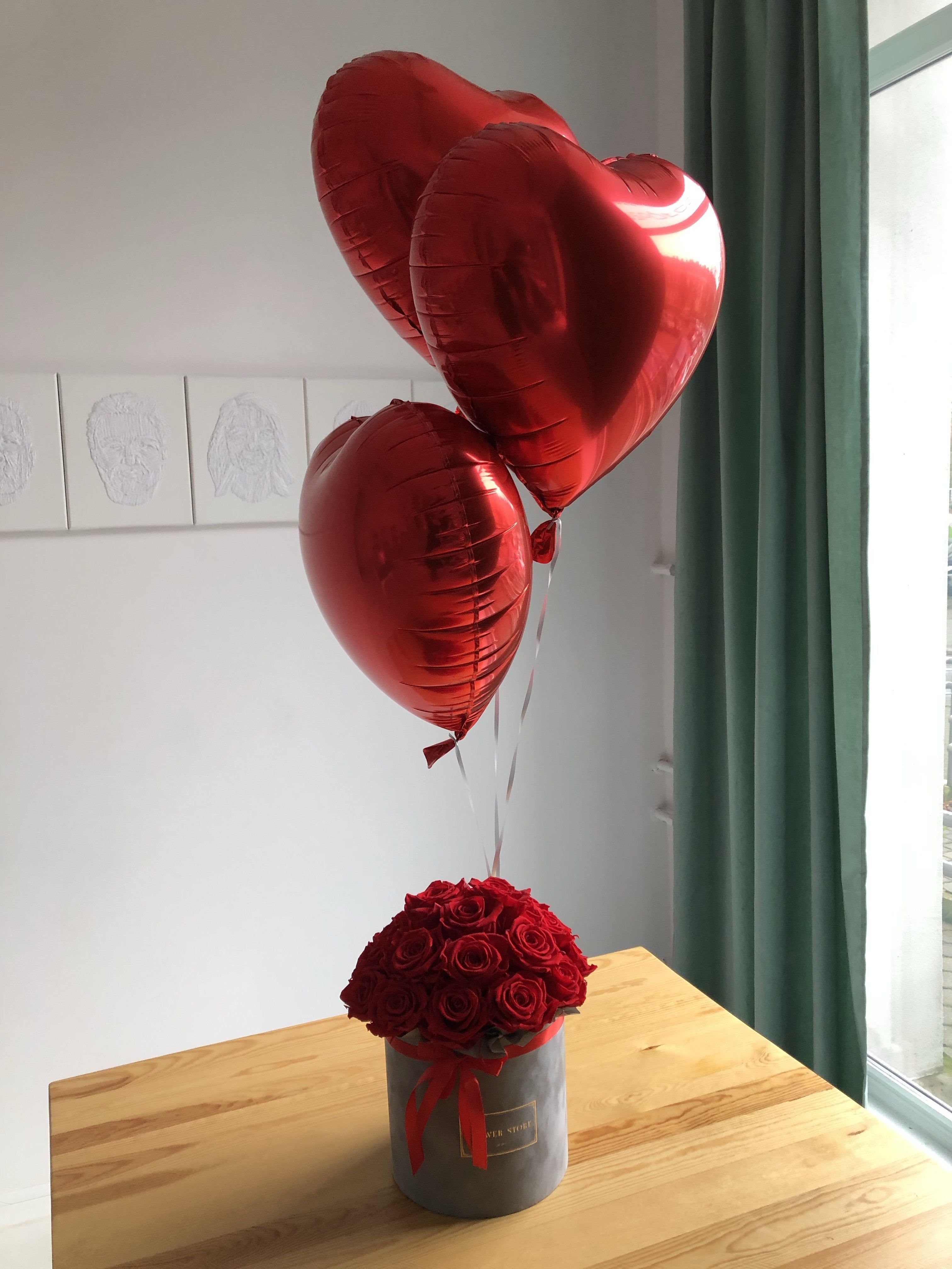 Набор красных воздушных шаров и серая коробка с розами - живыми цветами.