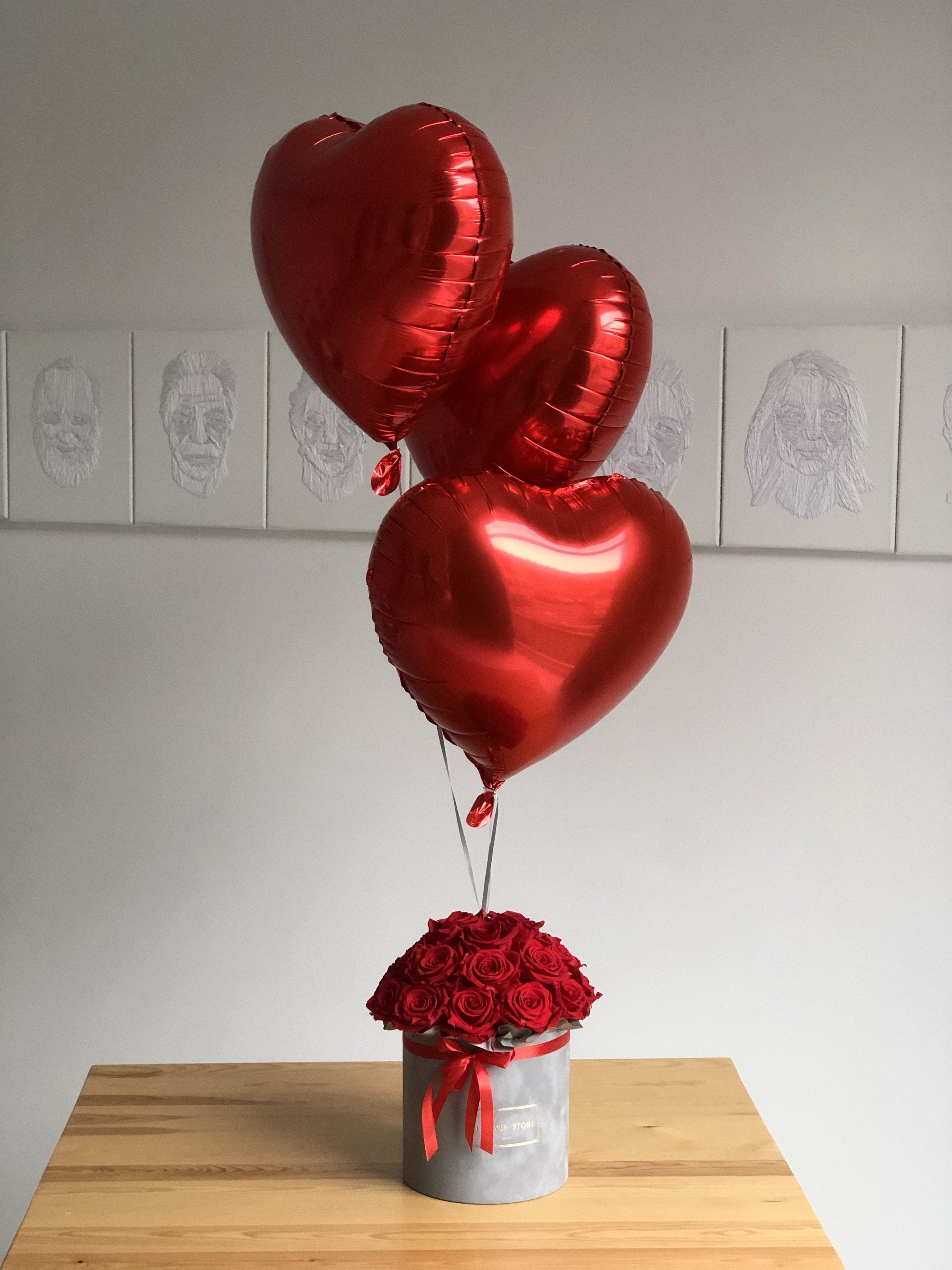 Набор красных воздушных шаров и серая коробка с розами - живыми цветами.