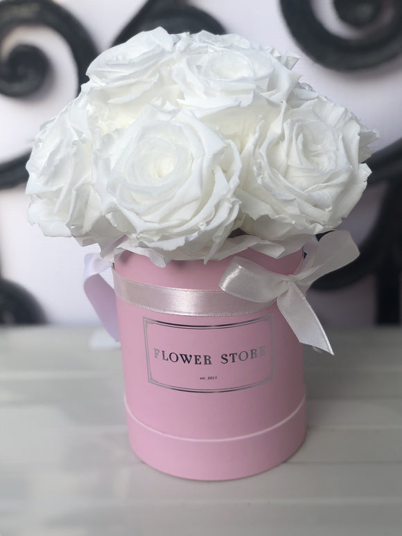A small pink box with white eternal roses